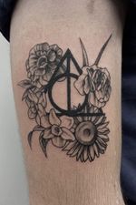 Deathly Hallows tattoo adorned with flowers by Brooke Ashby of Flow Tattoo #BrookeAshby #DeathlyHallowsTattoo #Blackwork #flowers #MeaningfulTattoo