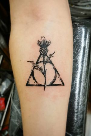 Feminine Deathly Hallows design featuring thistle and nature elements by Akos of Sanatorium Tattoo #Akos #DeathlyHallowsTattoo #thistle