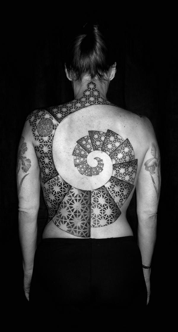 This geometric back tattoo by Tomas Tomas is using the Fibonacci spiral.