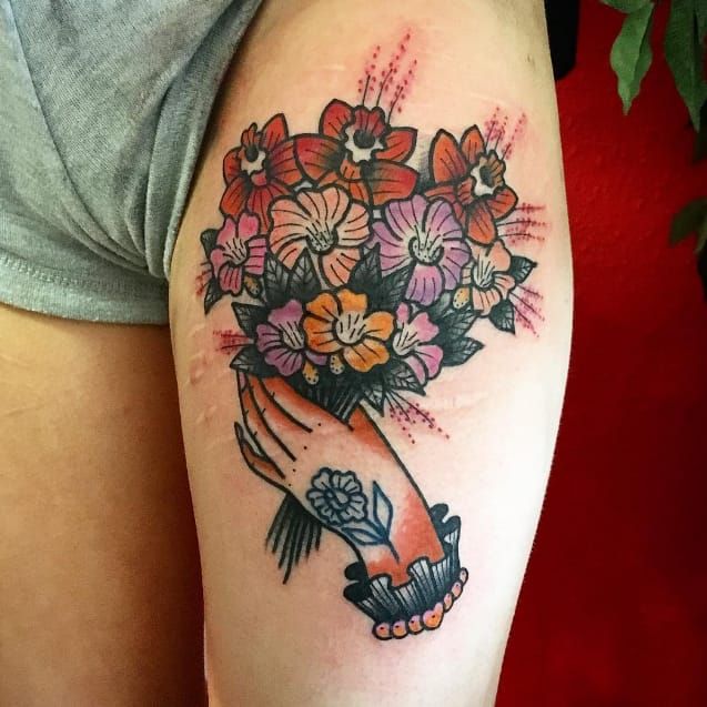 Line art hand holding flowers tattoo on the inner