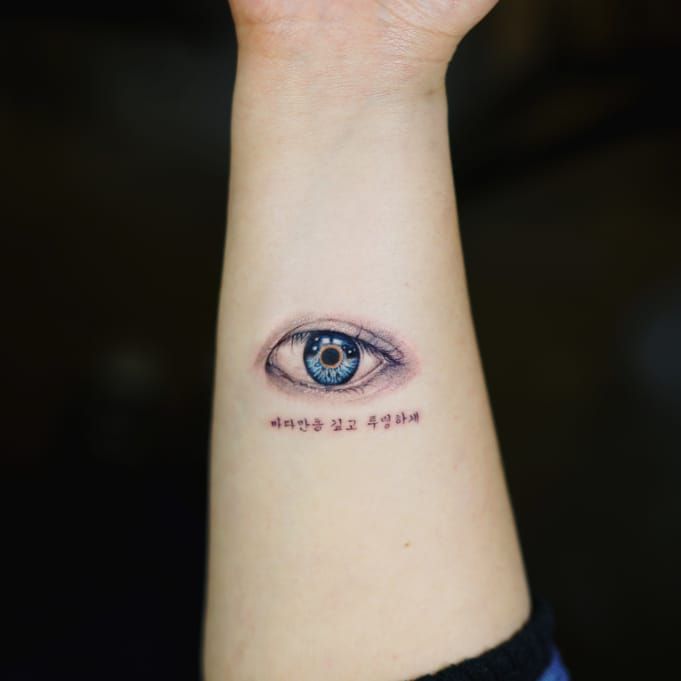 Small fine line style eye tattoo on the forearm