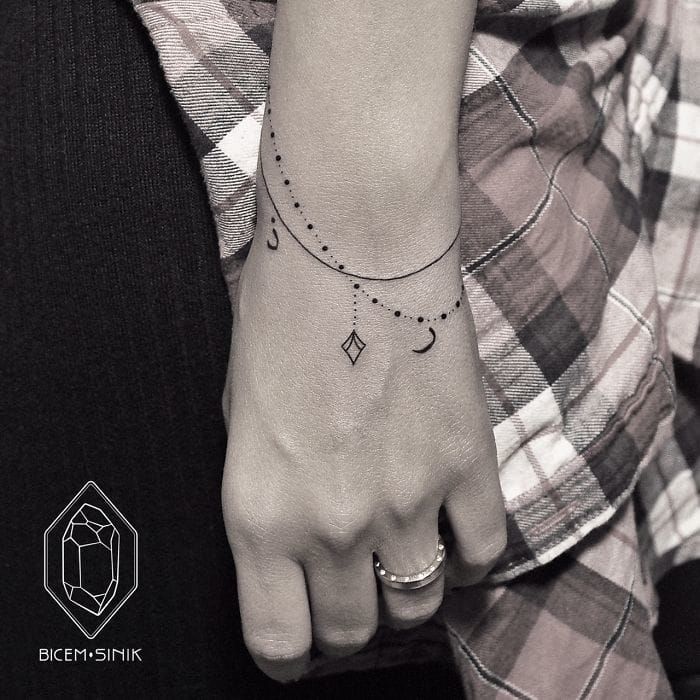 Wrist tattoos for women can look so delicate and elegant, a subtle and thin bracelet piece by Bicem Sinik adorned with a charms #diamond #bracelet #delicate #dotwork #linework