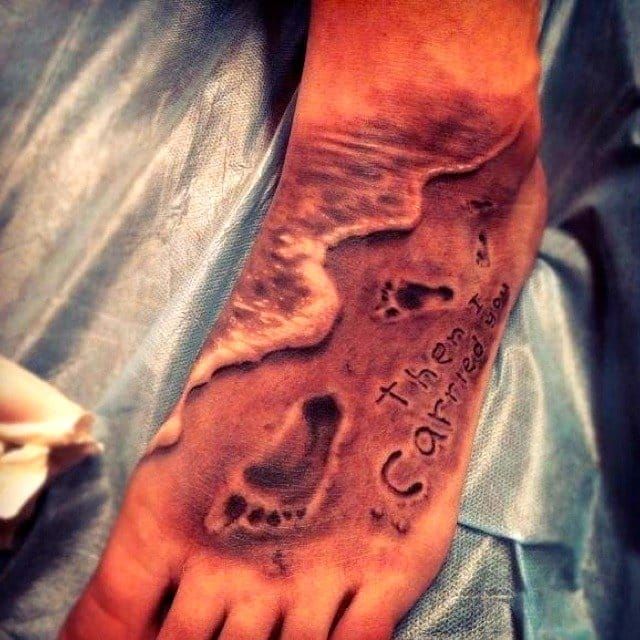 "...it was then that I carried you." The texture and depth in the sand, the ocean foam, well executed realism tattoo based on the poem Footprints, placed on the foot-how appropriate.