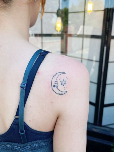 Laura's blackwork tattoo features a fine line illustration of a moon and star, creating an ignorant yet harmonious celestial design.