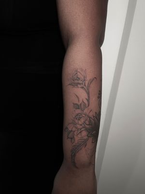 Elegant black & gray flower tattoo on dark skin, designed by Lauren with stunning realism.