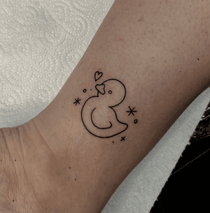 An adorable fine line heart tattoo featuring a cute doodle duck with sparkles, created by Kateryna Goshchanska.