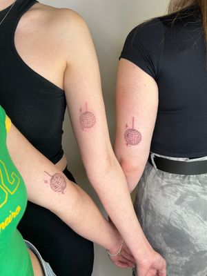 Get groovy with these sleek fine line tattoos by Emma InkBaby, featuring matching disco ball motifs. Perfect for celebrating friendship or love!