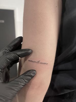 Get a sleek and understated touch with this fine line tattoo featuring small lettering by the talented artist Alina Amberland.