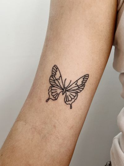 Laura's fine-lined butterfly tattoo features intricate hand-poked details, giving it a unique and delicate look.