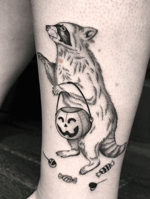 Illustrative tattoo by Amandine Canata featuring a mischievous raccoon with trick or treats and a pumpkin. Perfect for Halloween vibes!