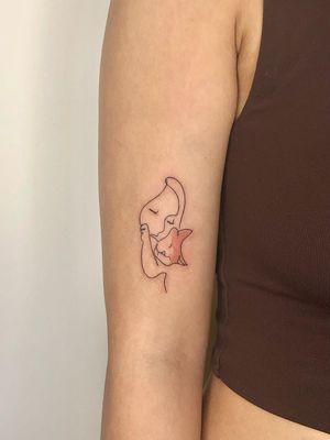 A minimalist fine line tattoo of a woman and cat in a single continuous line, by artist Winnie Shwe.