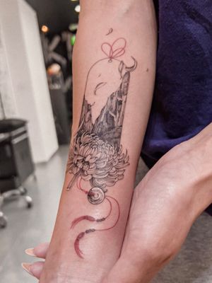 Evoke serenity with this fine line, illustrative tattoo by Alex Caldeira featuring majestic mountains, delicate flowers, and a magical portal.