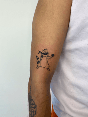 A unique anime-style tattoo of a playful raccoon, created by artist Joanna Webb. Bold lines and vibrant colors bring this mischievous creature to life.