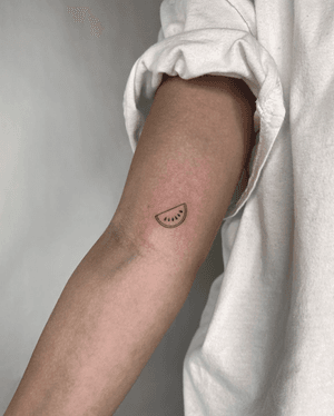 Fine line tattoo of a minimal watermelon slice done by Marissa Boulay.