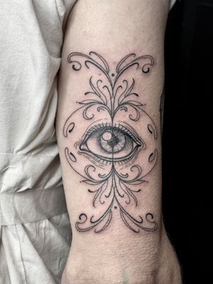 Experience intricate detailing and stunning design with this ornamental and illustrative eye tattoo by the talented artist Amandine Canata.