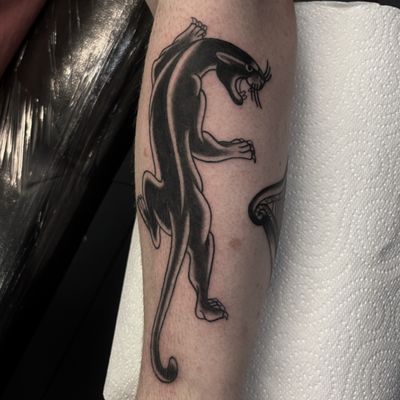 A striking blackwork tattoo of a fierce panther, created by Claudia Vicente in a traditional style.