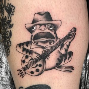 Get inked with this playful illustrative design featuring a frog playing a banjo in a cowboy hat, done by Megan Foster.