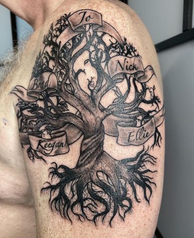 Unique black and gray tattoo featuring an illustrative tree with small lettering on a banner by Alfonso Barberio.