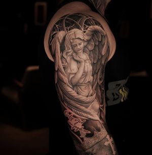 A black and gray realistic tattoo of an angel statue in a medieval church setting with detailed arches. By artist Ember.