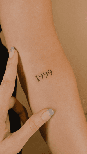 A minimalist lettering tattoo of a significant date created by Milky Blue.