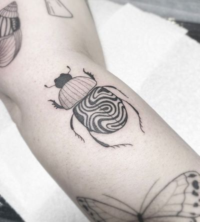 Explore the dark and detailed world of blackwork tattoos with this illustrative beetle design crafted by the talented artist Ali Bloom.