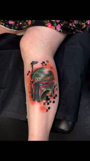 Vibrant watercolor tattoo on lower leg by Sandro Secchin, featuring iconic Boba Fett helmet in new school style.