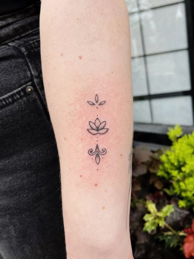 Hand-poked dotwork lotus design by artist Laura, intricate ornamental style.