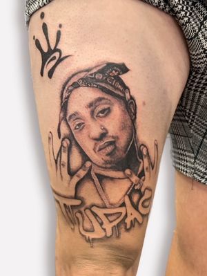 Get a stunning black and gray portrait tattoo of Tupac by artist Ellie Shearer. This realistic and illustrative design captures the essence of the legendary musician.