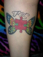 Autism puzzle piece with butterfly wings on left forearm