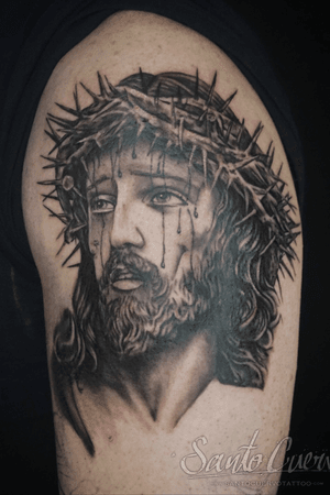 Capture the solemnity of Jesus with this black and gray upper arm tattoo featuring thorns, blood, and tears. Located in London, GB.