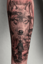 Black and grey, with a touch of red, realisitc scenery of a boy and a wolf meeting eachother. #blackandgrey #wolftattoo #realism 