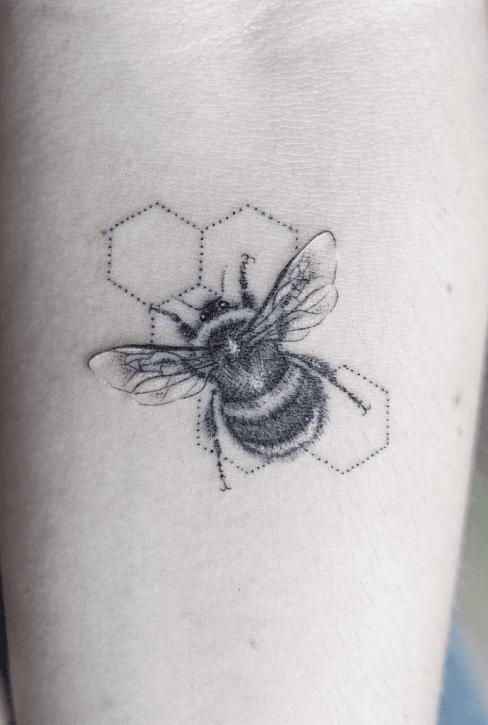 Fine line bee tattoo on the inner arm