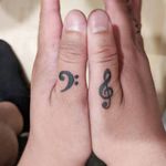 A treble clef and a bass clef on the client's thumbs