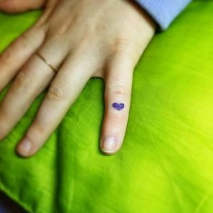 The tiniest purple heart on the client's top knuckle in the left pinky finger.