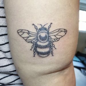 A fuzzy bumblebee on the back of the client's right arm, above the elbow.