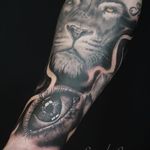Marvel at the intricate details of this black and gray lion and eye tattoo on the forearm by artist Alex Santo.