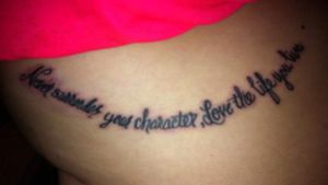 Under right boob. "Never surrender your character, love the life you live."