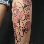 Beautiful lower leg tattoo of a colorful watercolor flower by artist Alex Santo.
