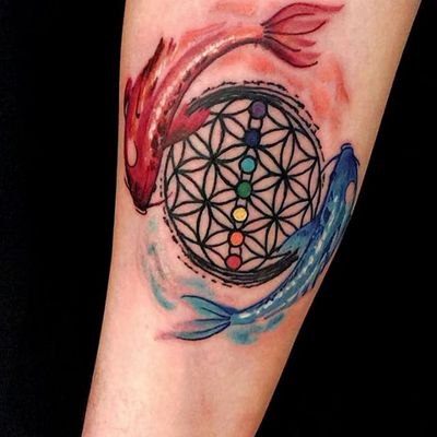 Unique forearm tattoo by artist Alex Santo, combining geometric shapes, vibrant watercolor hues, serene fish motif, and intricate mandala design.