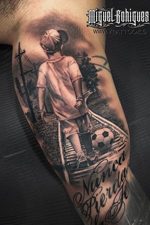A boy, a ball, walking on the railway, tattoo in the arm. 
