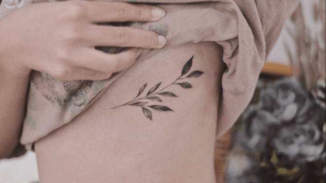 Fine line leaves tattoo located on the rib.