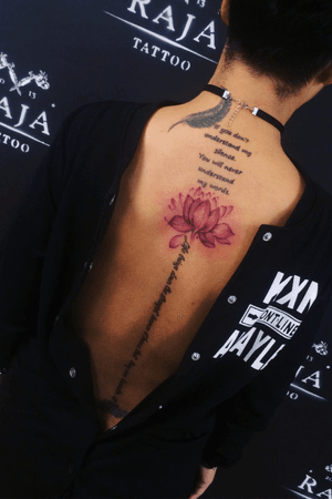 Color lotus tattoo on spine with some phrase