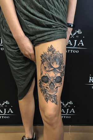 Skull tattoo woth flowers on women leg