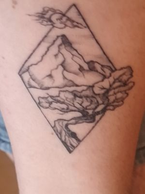 A diamond shape surrounding a mountain scenario. Perfect for a small first tattoo including a lot of small nimble details. 