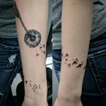 Dandelion puff blowing into birds forearm small first tattoo black and grey simple