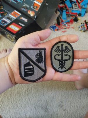 I would like to add these under the caduceus on my left upper arm. With the names of the units encircling them. I would like the surrounding area around my arm down to about two inches below my elbow and above the caduceus around my shoulder to be US Army Operational Combat Pattern camouflage since that was the last uniform I wore in the army. On my forearm, I would like surgical instruments such as a scalpel and forceps and scissors. On my right shoulder I would like the American flag patch that we use in the Army. On my chest I would like a map of the world with a small star in every country I've been in. I would like the map to be very brightly colored. And the USA to have a wavy American flag as it's color.