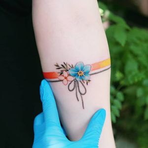 A rainbow spectrum band around her arm with grey knotted ribbon below it.🌈.#tattooistsion #flowertattoo #floraltattoo #Korea #KoreanArtist #tattooistsion #colortattoo #flower #flowers #oriental 