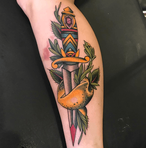 Vibrant traditional tattoo design by Darren Brass featuring oranges, dagger, and leaf motifs on lower leg.