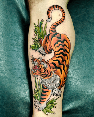 Traditional Japanese tattoo on the lower leg featuring a fierce tiger and delicate leaf motif by artist Darren Brass.