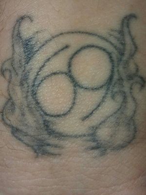 Stick and poke done with a staple and soot made from a burning chess piece. It is the cancer sign surrounded by smoke. Pretty good for a tattoo no bigger than a 50 cent piece 